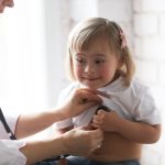 little girl with Down Syndrome having her heart chest checked by doctor with syhtescsope.