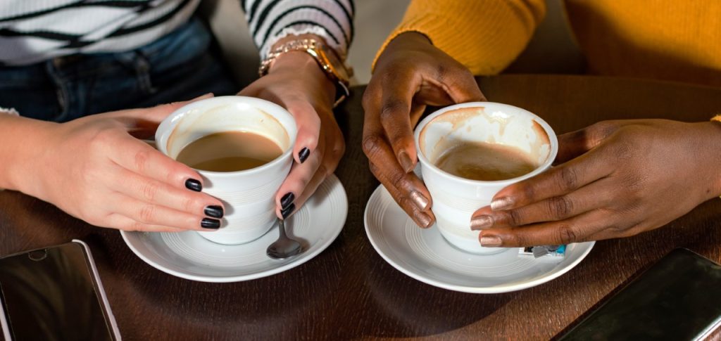two sets of hands each holding a coffee cup